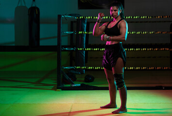 Portrait young Latina boxer woman wrapping hand with sport bandage on black background