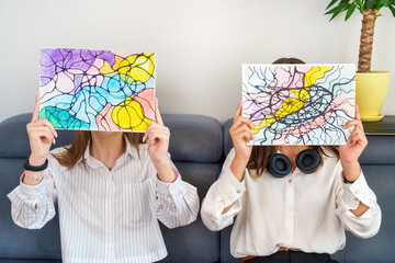 Teenage girls holding neurographic drawings, faces covered. Abstract neurographic drawing with markers and colored pencils. Colorful neurography - Powered by Adobe