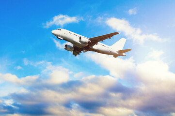 Airplane flying in the blue sky, travel background with airplane flying high over the clouds. Flying airplane with blank white livery