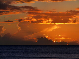 the sunset sky in vieux fort, guadeloupe. Sun disappearing in the clouds with horizon over...