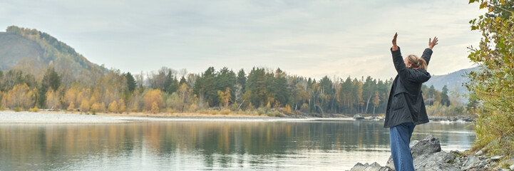 Peaceful autumn hike by serene lake with mature woman enjoying tranquil nature and vibrant fall colors.