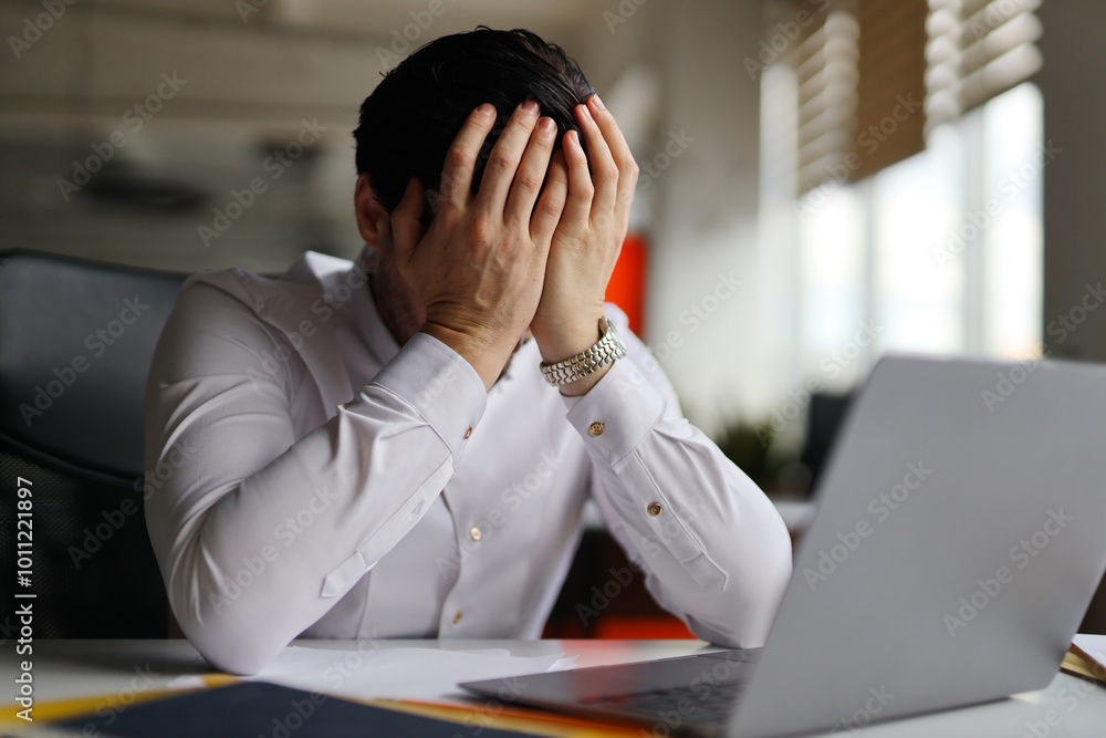 Aufkleber a man is sitting at a desk with a laptop and a stack of papers. he is crying and he is in distress