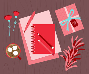 Top view of the desk with red color notebook, flowers, pen and blanks papers. Hot chocolate cup and pink gift box are in the background.