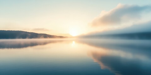 Fototapeta premium A serene sunrise over a tranquil lake, reflecting soft clouds and a misty landscape, perfect for peaceful nature imagery.