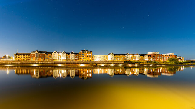Barnstaple at night, modern houses reflected in the river Taw. Long exposure