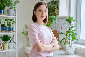 Portrait of young confident serious woman in home interior