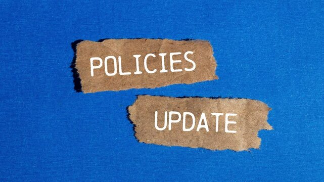 Policies update message writing on ripped torn brown paper pieces on blue background. Conceptual policies update symbol.