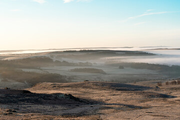 Stunning winter morning landscape with mist rolling over rolling hills and valleys in serene countryside