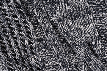 Background of gray knitted dense with white and black threads. Part of knitted sweater.