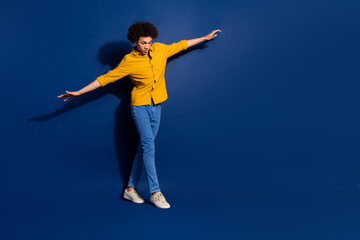 Full size photo of nice young man focused walk empty space rope isolated on dark blue color background © deagreez