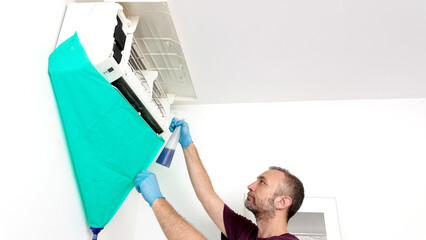 Man cleaning and maintaining air condition unit at home.