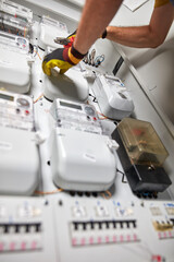 Technician working on a electricity power meter station in a building.