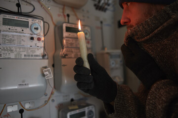 Checking the electricity power meter with a candle in cold winter days while there is power outage.