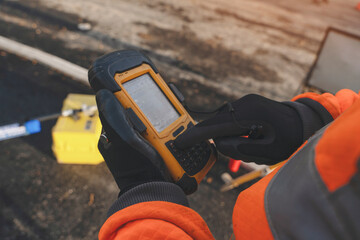 A worker using a rugged device at a construction site during a sunny day, ensuring safety and efficiency