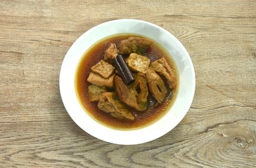 boiled tofu and textured vegetable protein vegetarian food in cinnamon herb brown soup on plate