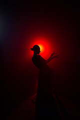 Silhouette of a woman in a red skirt dancing Latin in smoke in neon light. Dance concept. Bachata, Latina