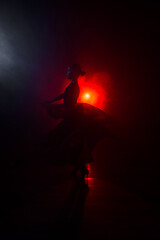 Silhouette of a woman in a red skirt dancing Latin in smoke in neon light. Dance concept. Bachata, Latina