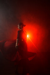 Fototapeta premium Silhouette of a woman in a red skirt dancing Latin in smoke in neon light. Dance concept. Bachata, Latina