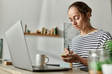A woman with vitiligo focuses on writing notes at her desk.