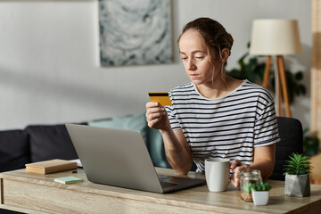 A woman with vitiligo thoughtfully reviews her credit card during study time.