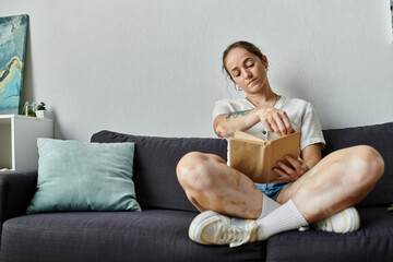 A woman with vitiligo enjoys a quiet moment reading a book at home.