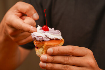 Cherry on top. Cupcake. Birthday cupcake with cherry on top. Happy Birthday. Bakery. Confectionery. Eating. Eating cupcake with a finger. Cupcake decoration.