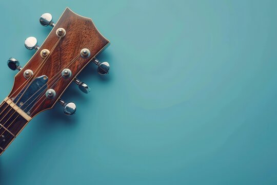 Acoustic guitar headstock on a blue background showcasing tuning pegs and wood grain texture
