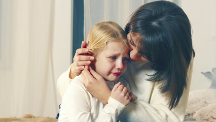 Mother comforting crying child in tender moment. A mother tenderly comforting her crying child,...