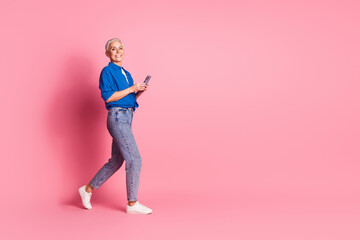 Full length photo of shiny attractive lady dressed blue shirt texting modern gadget empty space isolated pink color background