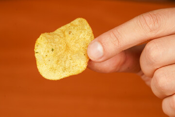 Hand holding potato chip closeup. Calories. Obesity. American food. Unhealthy lifestyle. Man eating potato chips. Fast food. Junk food.