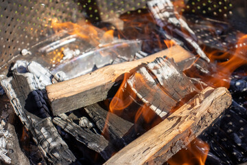 Burning wood and glowing embers create a warm and inviting atmosphere, perfect for outdoor gatherings and BBQs.