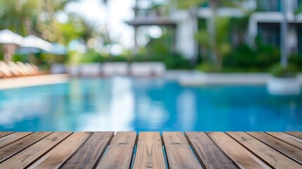 Empty wooden deck overlooking a blurred swimming pool and resort.