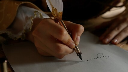 Antique young woman in renaissance dress sitting at table and writing letter with vintage quill pen...