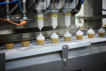 On the conveyor of the ice cream machine, the machine fills the waffle cups with the milk mixture.