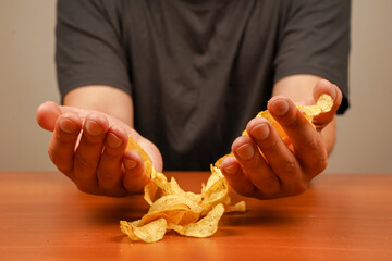 Man eating potato chips. A view of a hand holding a stack of ridged potato chips. Hand holds potato...