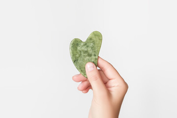 hand holding green heart shaped jade gua sha massager