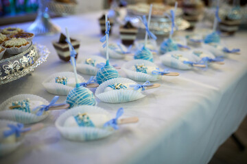 Various pastries and cakes on a beautifully served festive table on the background of a party with people.
