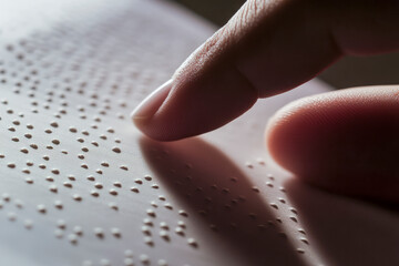 Close-up of fingers reading Braille text, highlighting the tactile experience of touch.