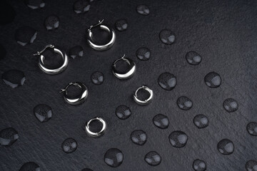 Set of metal jewelry close-up. Beautiful stylish earrings. Silver earrings with water drops on a...