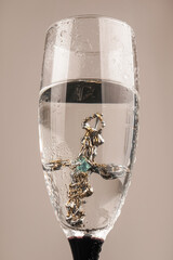 Viking Age pendant. A jewelry cross in a glass for alcohol. Silver cross on a dark background.