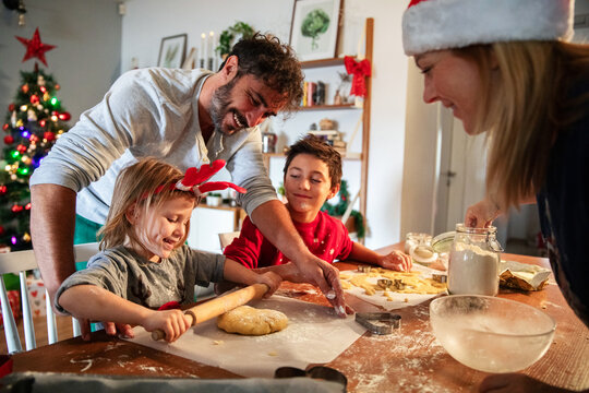 Family baking Christmas cookies together in festive kitchen with Christmas tree