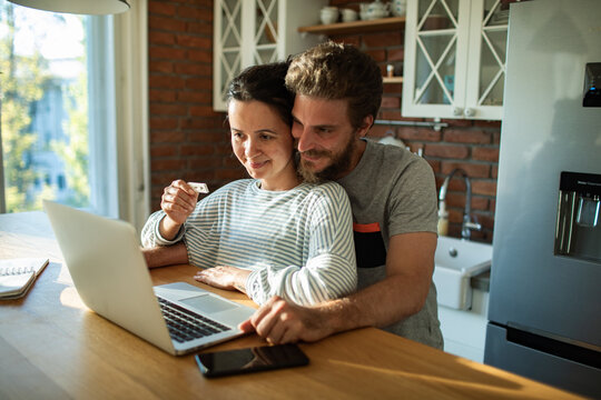 Couple showing positive pregnancy test to laptop video call at home