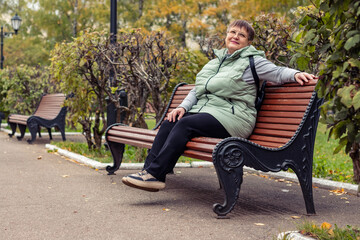Obraz premium An elderly woman with an umbrella is sitting on a bench.