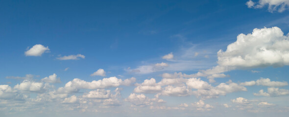 Fototapeta premium Clear blue sky with fluffy white clouds, ideal for backgrounds or natural landscapes