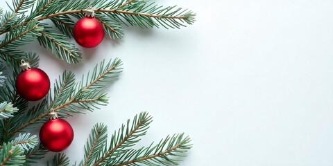 Green pine tree branches with red Christmas ornaments on a white background