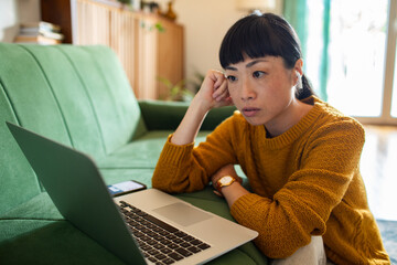 Focused woman working on laptop while sitting on the floor