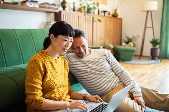 Couple using laptop together on the living room floor