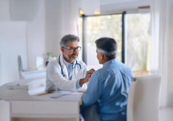 Obraz premium A doctor in a white coat with a stethoscope listens intently as he speaks to a patient.