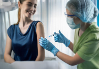 Obraz premium A woman is being injected in the arm by a healthcare professional.