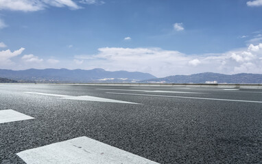 Expansive Road Under Clear Blue Sky with Hills in the Background